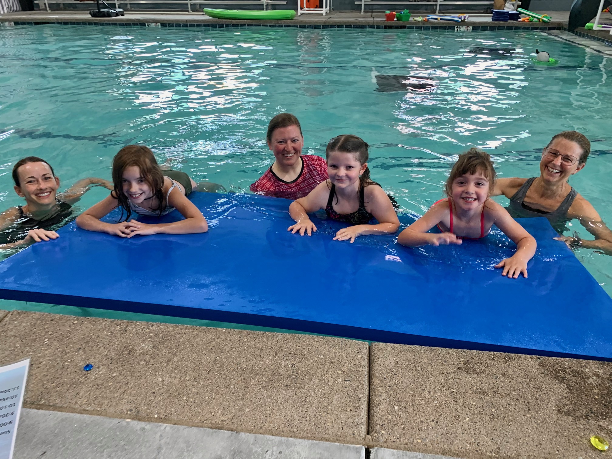 Our Medford therapists and clients during Aquatic Therapy at MCT. The therapists are in the pool with their children clients as they rest on a floating swimming mat.